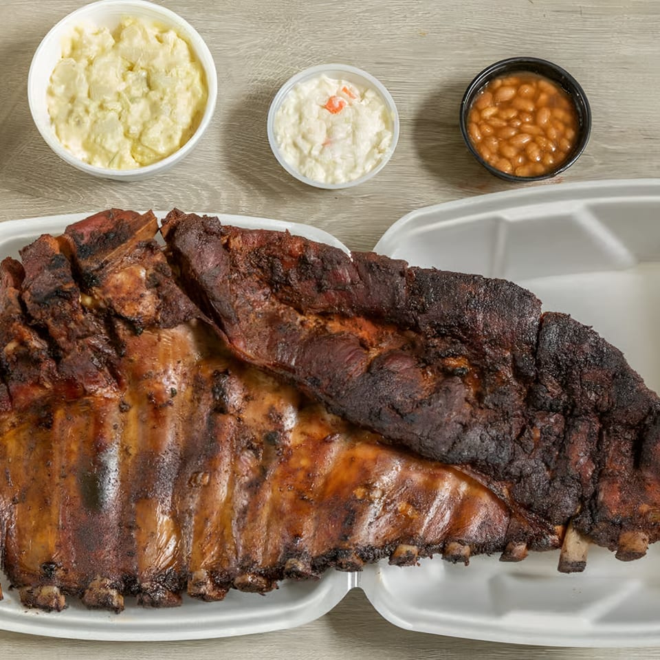 Ashley's Bar-B-Que ribs with sides of potato salad, coleslaw, and baked beans.